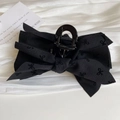 Detailed view of a black fabric bow hair claw clip with delicate embroidery on white cloth - Black Bow Claw Clip