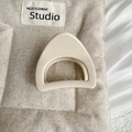 Détail d'une pince à cheveux géométrique beige mat sur un fond en tissu texturé - Style Triangle Large / Blanc