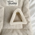 Détail de la pince à cheveux triangulaire crème avec ressort doré sur tissu beige - Style Triangle Mince / Blanc