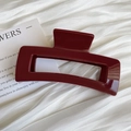Macro detail of glossy wine red rectangular hollow hair claw on soft white pleated fabric - Square Style