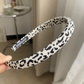 Dettaglio del cerchietto fatto a mano con stampa leopardata e un'etichetta in tessuto premium - Stampa Leopardata Bianca