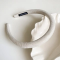 Primer plano detallado de una diadema de terciopelo beige con etiqueta artesanal interior - Blanco