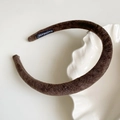Diadema de terciopelo marrón con etiqueta artesanal sobre plato de cerámica - Café Oscuro