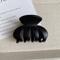 Detail of matte black octopus hair claw clip on beige linen surface with card - Matte Black