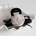 Detail einer eleganten Samt-Rosen-Haarklammer mit schwarzer Schleife in einer Schale - Weiß