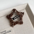 Close-up of a brown knit star hair clip with soft fuzzy texture and black metal BB base - Coffee Star Style
