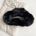 Close-up of black fuzzy plush large hair claw clip on minimalist beige fabric background - Black