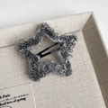 Detailed view of a star-shaped gray plush hair clip resting on a beige linen fabric tray - Grey Star Style