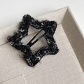 Detail of star-shaped black tweed hair clip with white plush yarn on beige linen tray - Black Stars Style