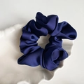 Detailed close-up of a high-gloss navy blue satin scrunchie resting on a white shell tray - Navy Blue