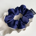 Close-up of navy blue satin scrunchie with white piped edges and embroidered textile label - Navy Blue With Piping
