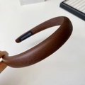 Detail of dark brown leather headband with handmade label and grain texture - Brown