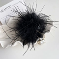 Close-up of black feather hair claw clip with gold pearl tassels on a white shell plate - Black