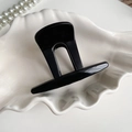 Glänzende schwarze minimalistische Haarklammer auf einer eleganten weißen Schale - Hellschwarz