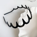 Dettaglio di un cerchietto nero ondulato in resina con denti antiscivolo su vassoio bianco - Etichetta Dorata Ondulata Con Denti / Nero