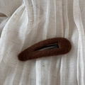 Vue détaillée d'une pince à cheveux marron en peluche en forme de goutte sur fond beige - Marron