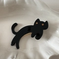 Detailed view of high-gloss black cat hair clip on a white ceramic display tray - Black