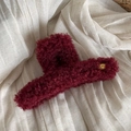 Macro shot of burgundy plush hair claw clip with golden Korea oval metal label - Red