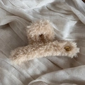 Detailed close-up of beige plush hair claw clip with oval gold logo and soft faux fur texture - Off-white