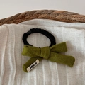 Detail eines Strick-Haargummis mit Nice-Label auf olivgrünem Stoff im Korb - Grün
