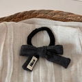 Détail d'un chouchou noir avec nœud en laine grise et étiquette tissée Nice - Gris Foncé