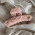 Close-up of pink plush shark hair clip with oval golden Korea tag on soft fabric - Pink