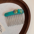 Detailed macro view of a teal acetate hair comb with a purple gradient bow on wood - Green