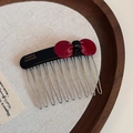 Detail of dark red acetate bow hair comb with silver metal teeth on a wooden tray - Black Red