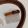 Detail of tortoise shell acetate bow hair comb with handmade metal teeth on linen base - Brown