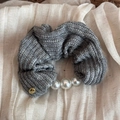 Gros plan d'un chouchou en maille grise avec perles blanches et bouton doré en métal - Gris