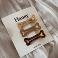 Three bone-shaped acetate hair clips in brown tones on a white display card detail - Bone Style