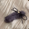 Detalle de pinza para el pelo de felpa gris con lazo negro y etiqueta de metal dorado - Morado