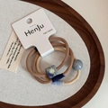 Gros plan de trois élastiques à cheveux avec perles bleues et marron sur plateau bois - Set de 3 pièces / Ensemble Perles Carrées Café