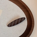 Detailed view of dark brown shark hair clip with white stripes on a wooden tray - Matte Stripe-Long Oval Clip / Brown