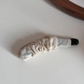 Détail de la texture en tissu plissé blanc crème sur une pince à cheveux banane rétro - Flocage - Pince Banane Beige