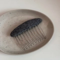 Close-up of grey felt fabric texture and metallic silver comb teeth for hair styling - Oval Fabric Comb-Gray