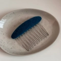 Detailansicht der dunkelblauen Filztextur auf einem silbernen Metall-Haarkamm mit 10 Zähnen - Ovale Stoffkamm-Blau