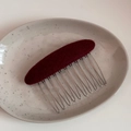 Nahaufnahme eines weinroten ovalen Stoff-Haarkamms mit silbernen Metallzähnen im Vintage-Stil - Ovale Stoffkamm-Rot