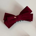 Close-up of a burgundy velvet double-layered bow hair clip with a golden metal logo tag - Red