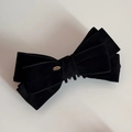 Close-up of velvet bow hair clip with a golden Love engraving on a metal tag - Black