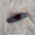 Close-up of a grey knitted oval hair clip with a red heart on beige linen fabric - Gray