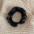 Detailed macro of black fabric hair scrunchie with colorful wool accents on knit background - Basic Style / Black
