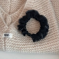 Detail of a black bow scrunchie with white dotted edges on a knitted sweater - Black (Dotted Edge Style)