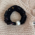 Detail of black tweed scrunchie with large pearl accent on beige knit background - Pearl Decorated Style / Black