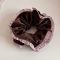Close-up of brown corduroy scrunchie with light purple ruffled satin edge detail - Brown