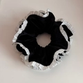 Detail view of large black velvet scrunchie with elegant double-layered white lace edges - Black