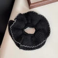Detailed close-up of a large black knit scrunchie with silver wavy stitched edges - Black