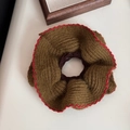 Detail of knitted oversized scrunchie with scalloped red edges and soft wool texture - Green