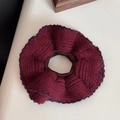 Macro shot of burgundy knitted scrunchie with navy blue wavy edges and thick fiber texture - Red
