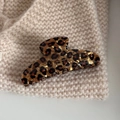 Dettaglio di un fermaglio per capelli leopardato su sfondo in tessuto beige a maglia - Pinza Grande a Ventaglio / Tartaruga Caffè Giallo